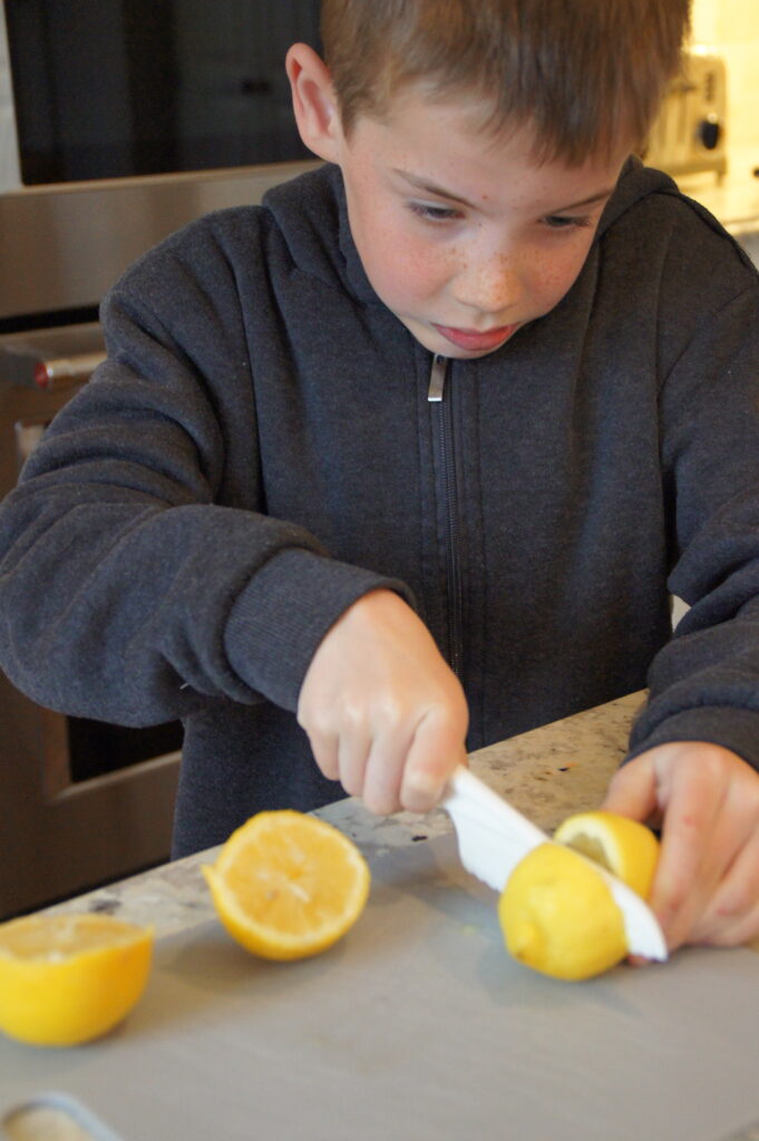 Jack helping me to slice lemons on a cutting board.