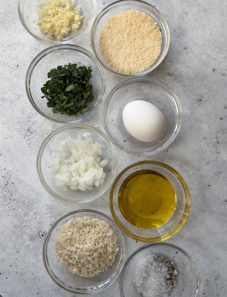 8 small bowls filled with panko bread crumbs, grated parmesan cheese, egg, olive oil, garlic and onion