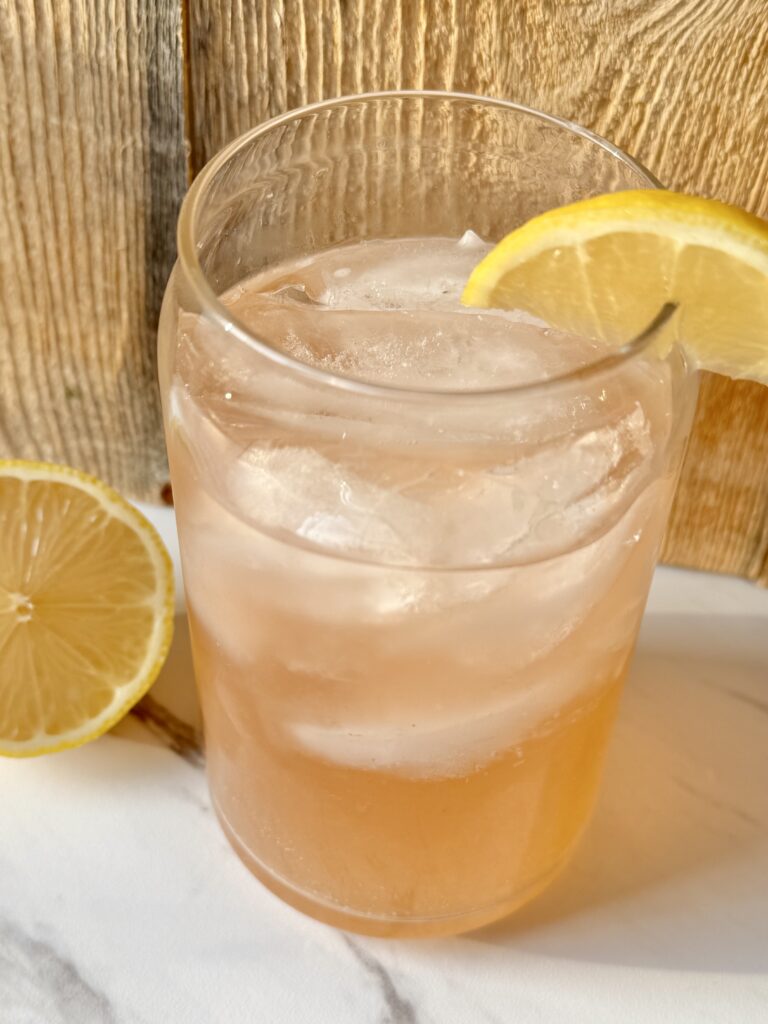 A glass filled with ice and sparkling water. Topped with a splash of bitters, fresh squeezed lemon and a lemon wedge.