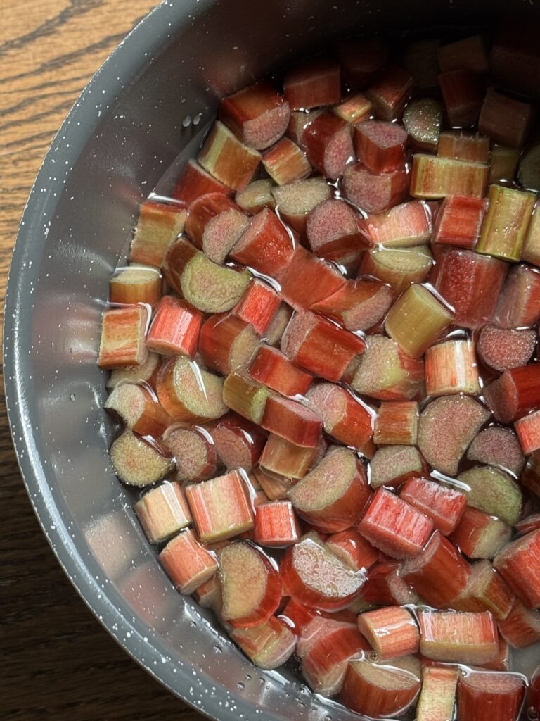 A pan filled with water, cut up rhubarb and sugar.